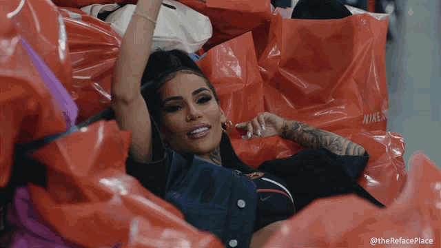 a woman is laying in a pile of nike plastic bags