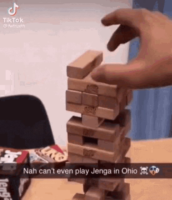 a person is stacking wooden blocks on top of each other to play jenga .