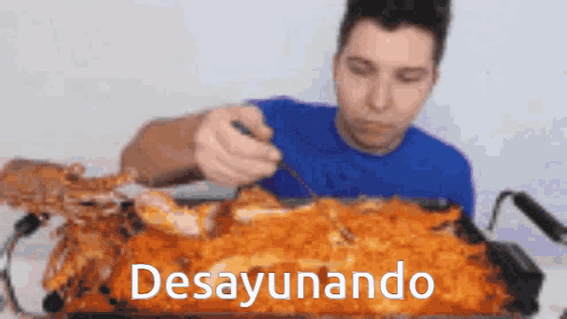 a man in a blue shirt is eating a large amount of food with the words desayunando written on the bottom