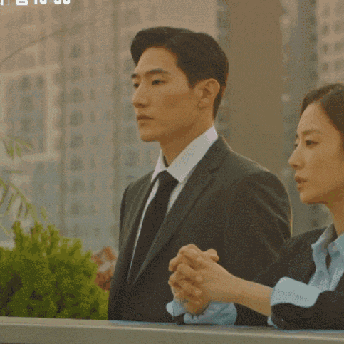a man in a suit and tie stands next to a woman in a blue shirt