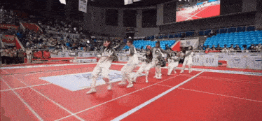 a group of girls are dancing on a red carpet in a stadium .
