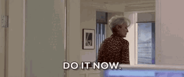 a woman in a leopard print shirt is standing in a room .