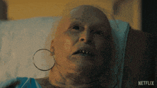 a woman with a bald head is laying in a hospital bed with a netflix logo in the background