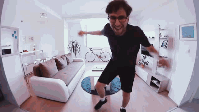 a man in a black shirt is dancing in a living room