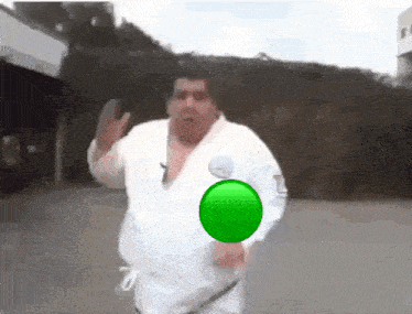 a fat man in a white karate uniform is running with a green circle in his chest .