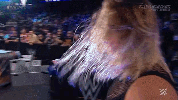 a woman in a wrestling ring with a wwe logo on her chest