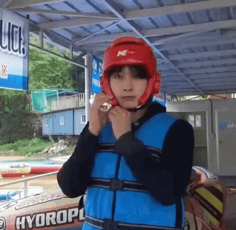 a man wearing a life vest and a red helmet is standing in front of a sign that says hydroplane