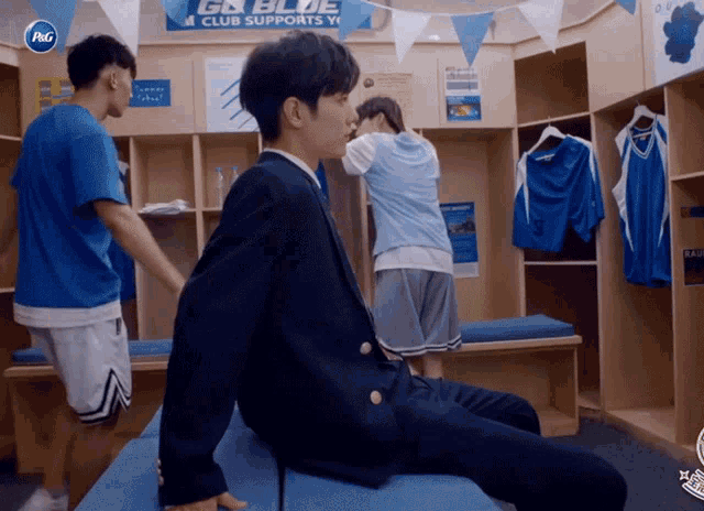 a man sits in a locker room with a p & g logo on the wall