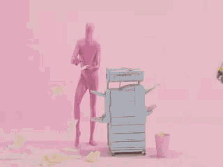 two pink figures are standing next to a printer on a pink surface