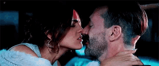a man and woman are kissing in a car .