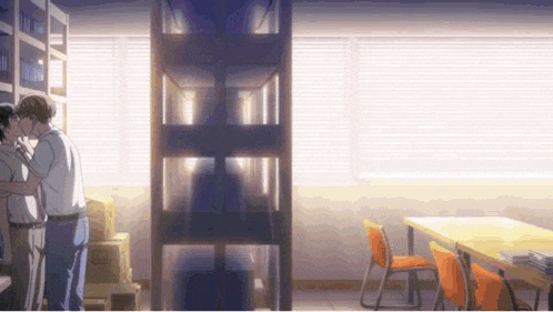 a man is kissing another man in a room with a table and chairs .