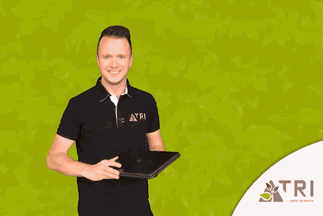 a man is holding a laptop in front of a green background with the word tri on it