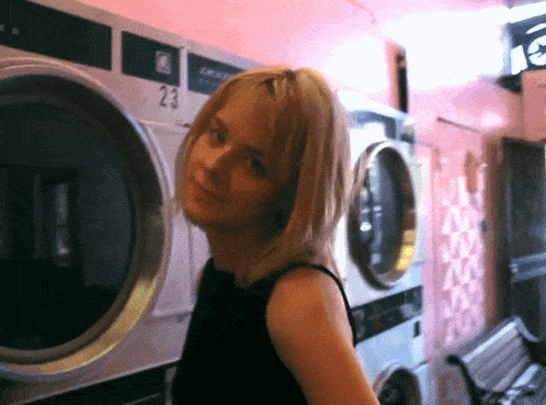 a woman is standing in front of a washing machine that has the number 23 on it
