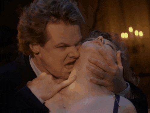 a man is holding a woman 's neck with his hand