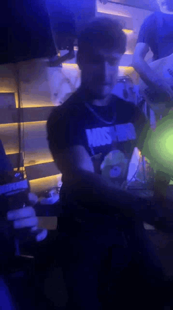a man wearing a black shirt that says just do it is dancing in a dark room