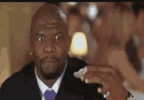 a man in a suit and tie is sitting at a table eating a piece of food .