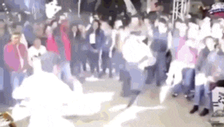 a blurry picture of a crowd of people watching a person dancing in front of them .