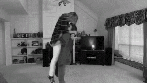 a black and white photo of a man holding a woman in his arms in a living room .