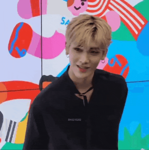 a young man in a black shirt is standing in front of a colorful painting .