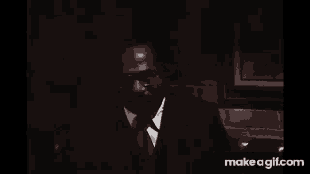 a man in a suit and tie is standing in a dark room .