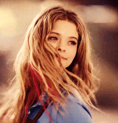 a woman with long blonde hair is wearing a blue shirt and red hair extensions