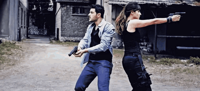 a man and a woman are holding guns while walking down a dirt road