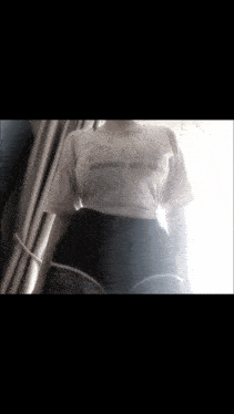 a woman wearing a white t-shirt that says hello kitty on it is standing in front of a window