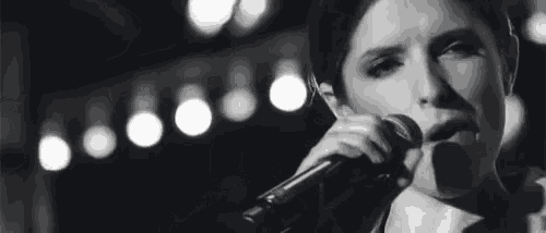 a black and white photo of a woman singing into a microphone
