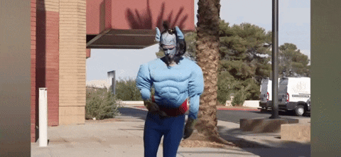 a man in a superhero costume is walking down a sidewalk