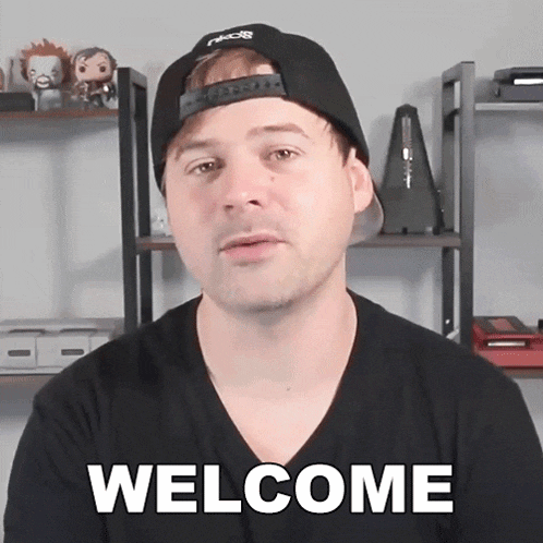 a man wearing a black hat and a black shirt says " welcome "