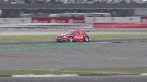 a red race car is driving on a track and the word castrol is on the back