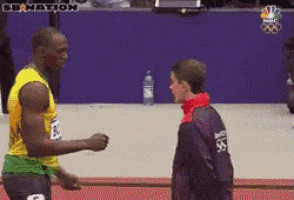 a man wearing a jacket with the number 96 on it talks to another man