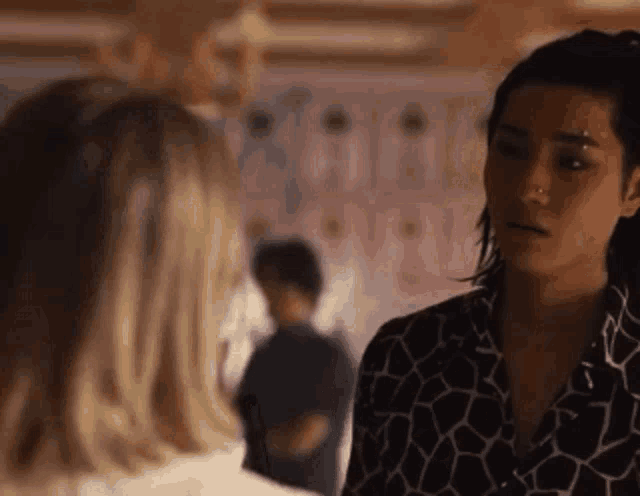 two women are standing next to each other in a room and talking to each other .