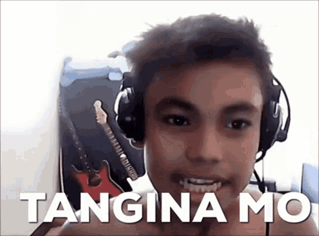 a young boy wearing headphones says tangina mo in front of a red guitar