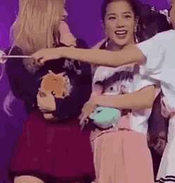 a group of women are standing next to each other on a stage . one of the women is holding a stuffed animal .