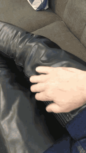 a person is sitting on a couch with their hands on their pants