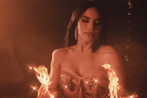 a woman with a tattoo on her arm holds a torch of fire
