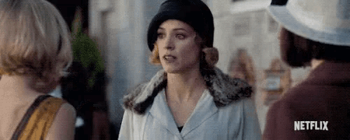 a woman in a hat is standing next to a man in a hat and talking to two other women .