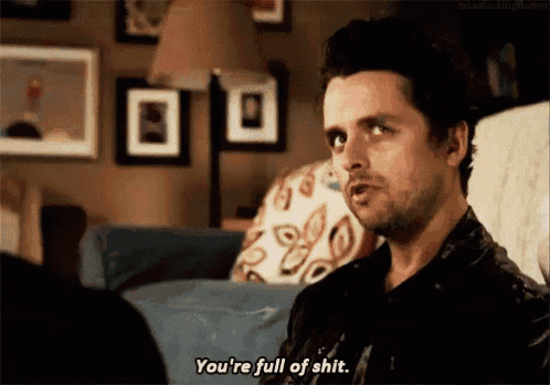 a man is sitting on a couch talking to another man and says you 're full of shit