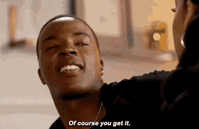 a man is smiling and saying `` of course you get it '' while looking at a woman .