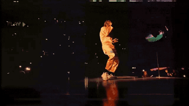 a man in a costume is dancing on a stage with a play button in the background