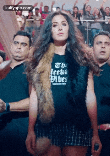 a woman is standing in front of a crowd wearing a black shirt that says the ielts vibes .