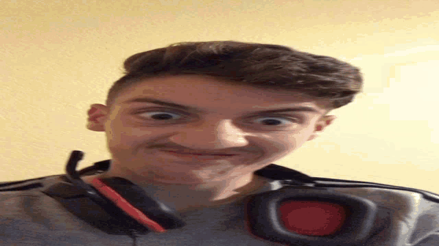 a young man with headphones around his neck making a funny face