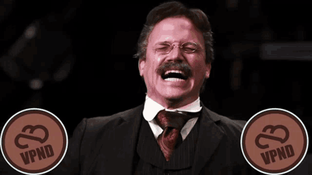 a man in a suit and tie is laughing with a speech bubble that says " what 's up vapor fam "