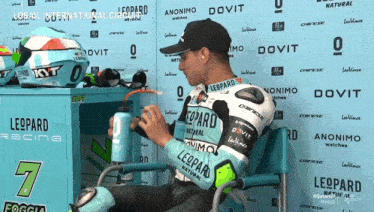 a man wearing a leopard racing jersey sits in front of a wall