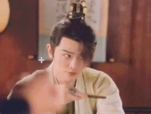 a man in a kimono is sitting at a table with chopsticks in his hand .