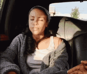 a woman is sitting in the back seat of a car with her eyes closed