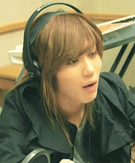 a woman with long hair wearing headphones looks at the camera