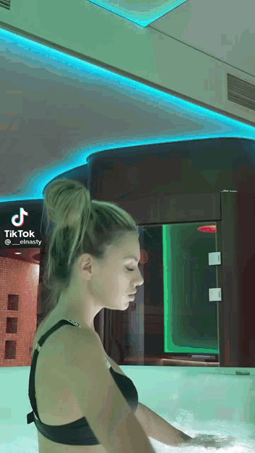 a woman in a black bra is standing in a bathtub with tiktok written on the bottom right