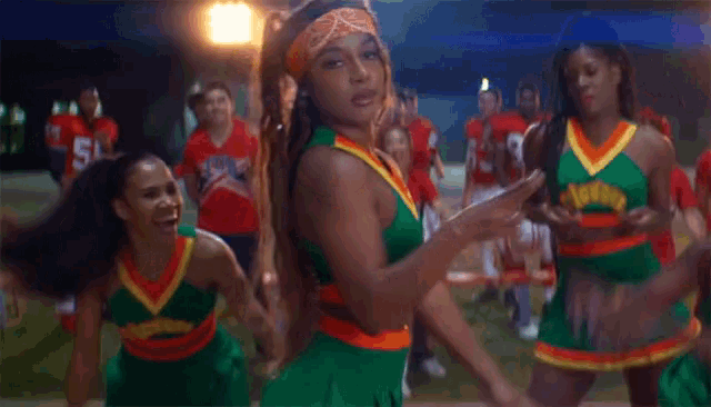 a group of cheerleaders are dancing in front of a group of football players one of whom is wearing number 38